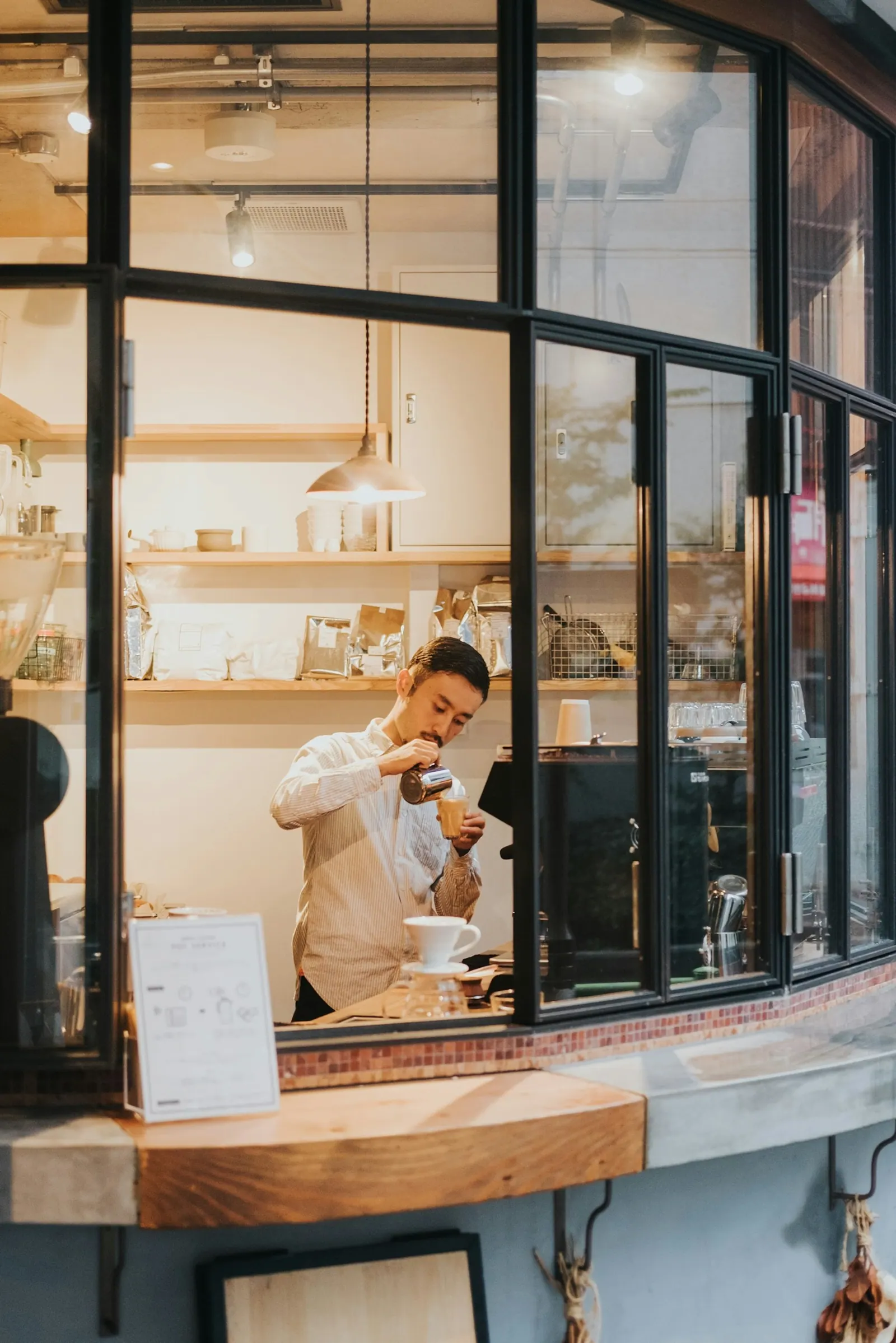 Barista připravuje kávu v okně malé kavárny